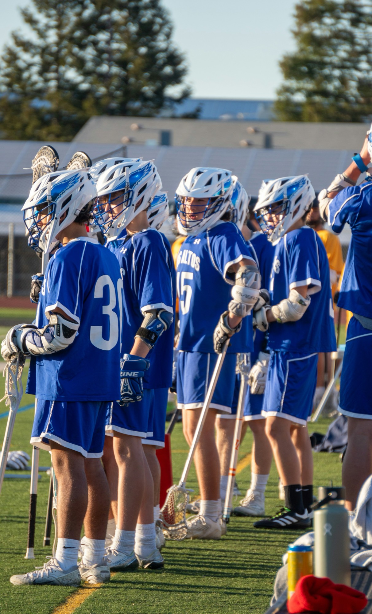 Youth lacrosse team on the sideline in golden-hour light — a closing image for Team Scout's where-teams-come-together section