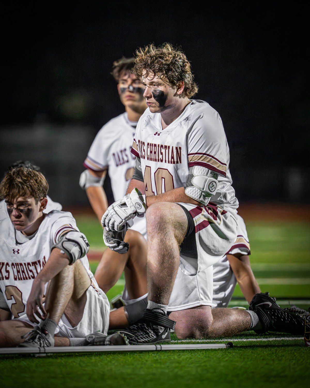 Lacrosse players kneeling on the sideline before a game