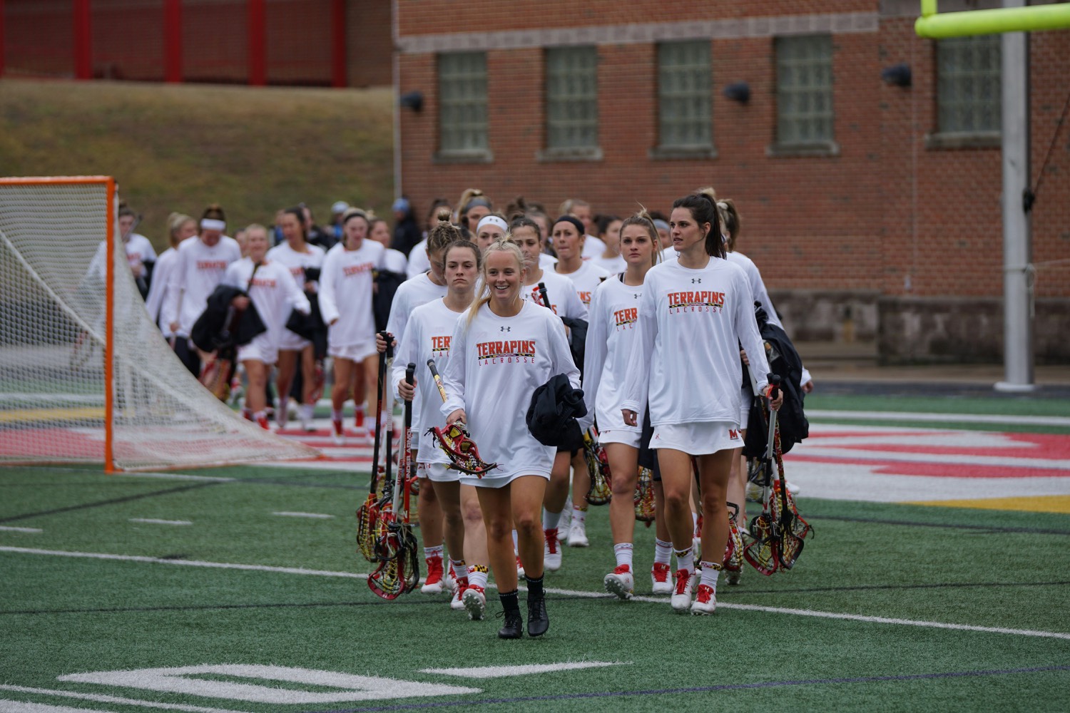 A women's lacrosse team walking out onto the field together