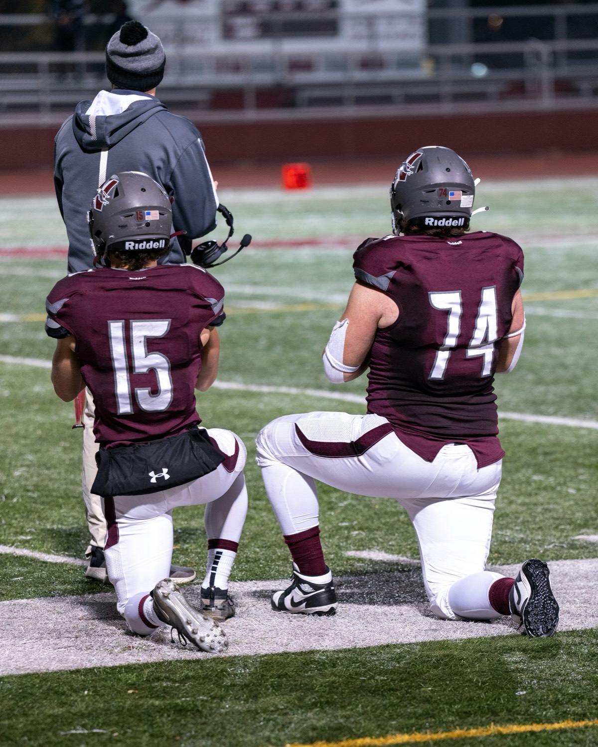 Young football players kneeling beside their coach before a game