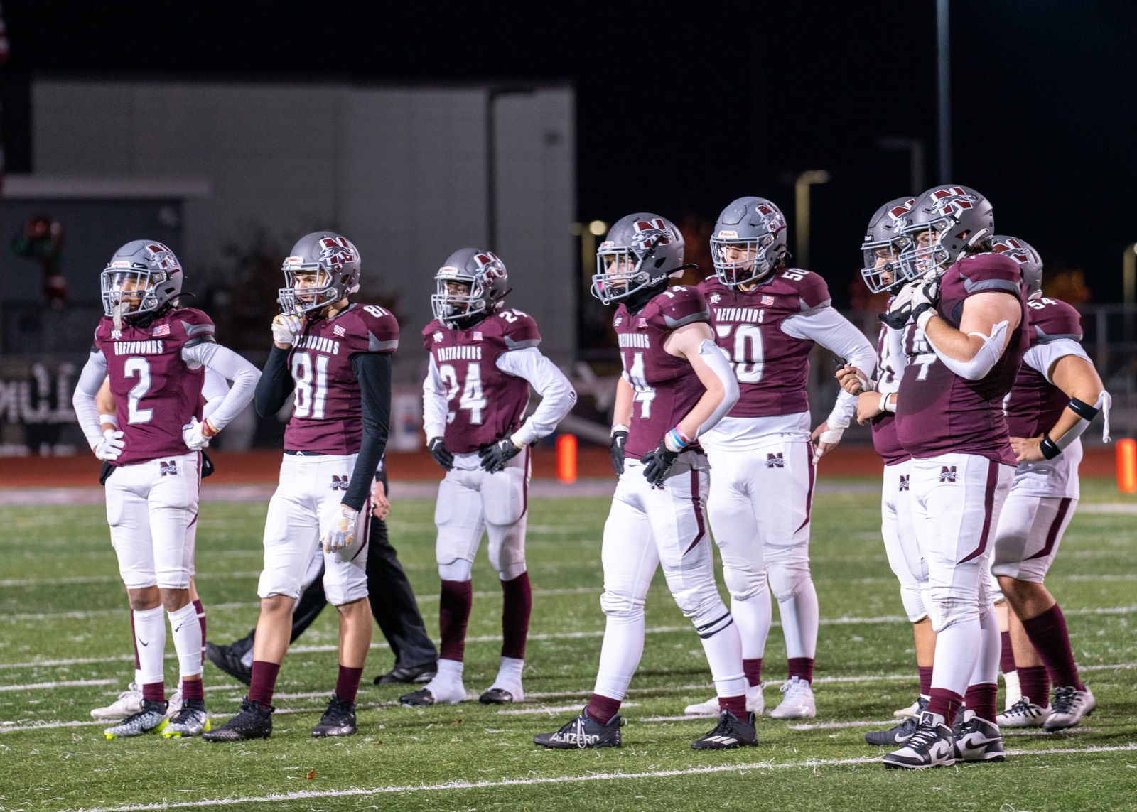 A youth football team standing together on the field under the lights